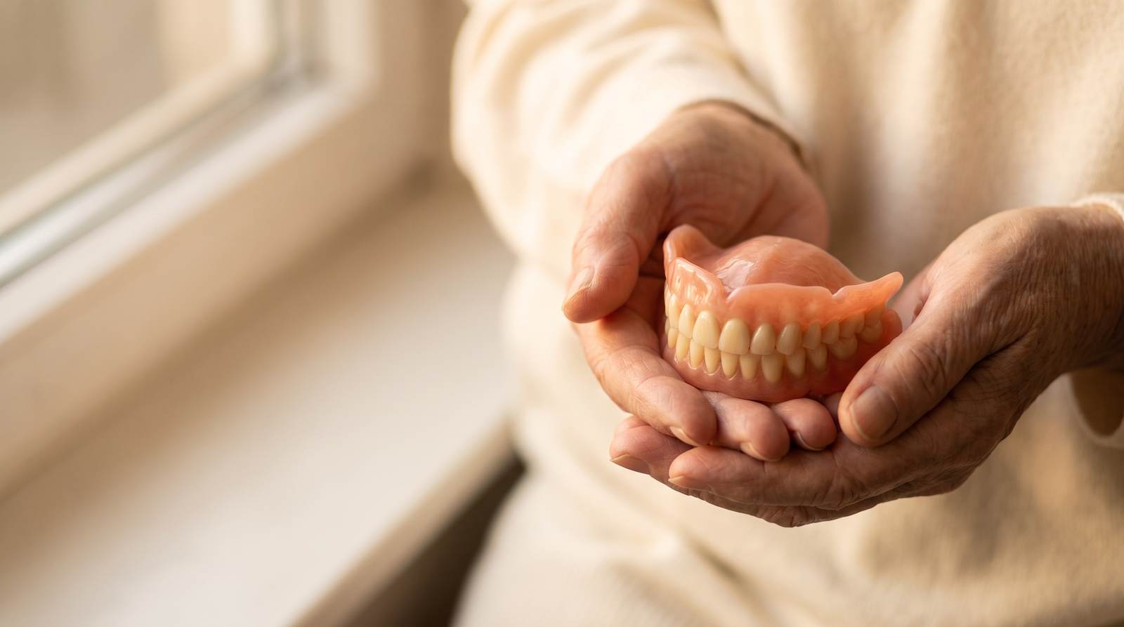 A complete denture held gently in two hands